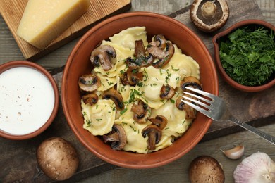Photo of Delicious ravioli with mushrooms and ingredients on wooden table, flat lay