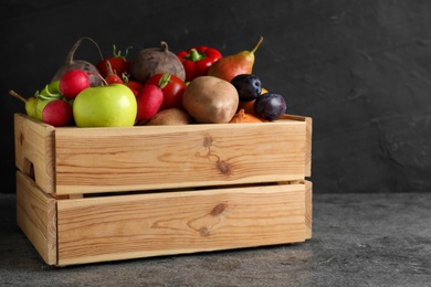 Photo of Wooden crate full of different vegetables and fruits on grey table. Harvesting time