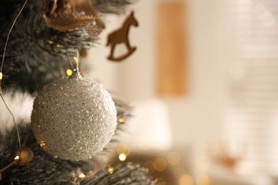 Beautiful decorated Christmas tree with fairy lights in room, closeup. Space for text