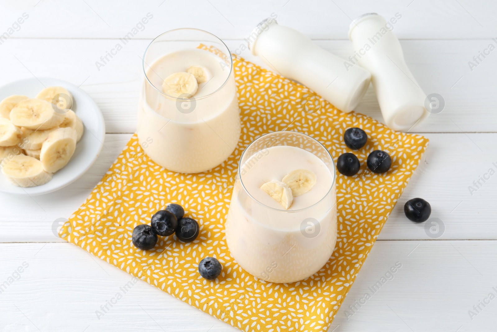 Photo of Tasty yogurt, banana and blueberries on white wooden table