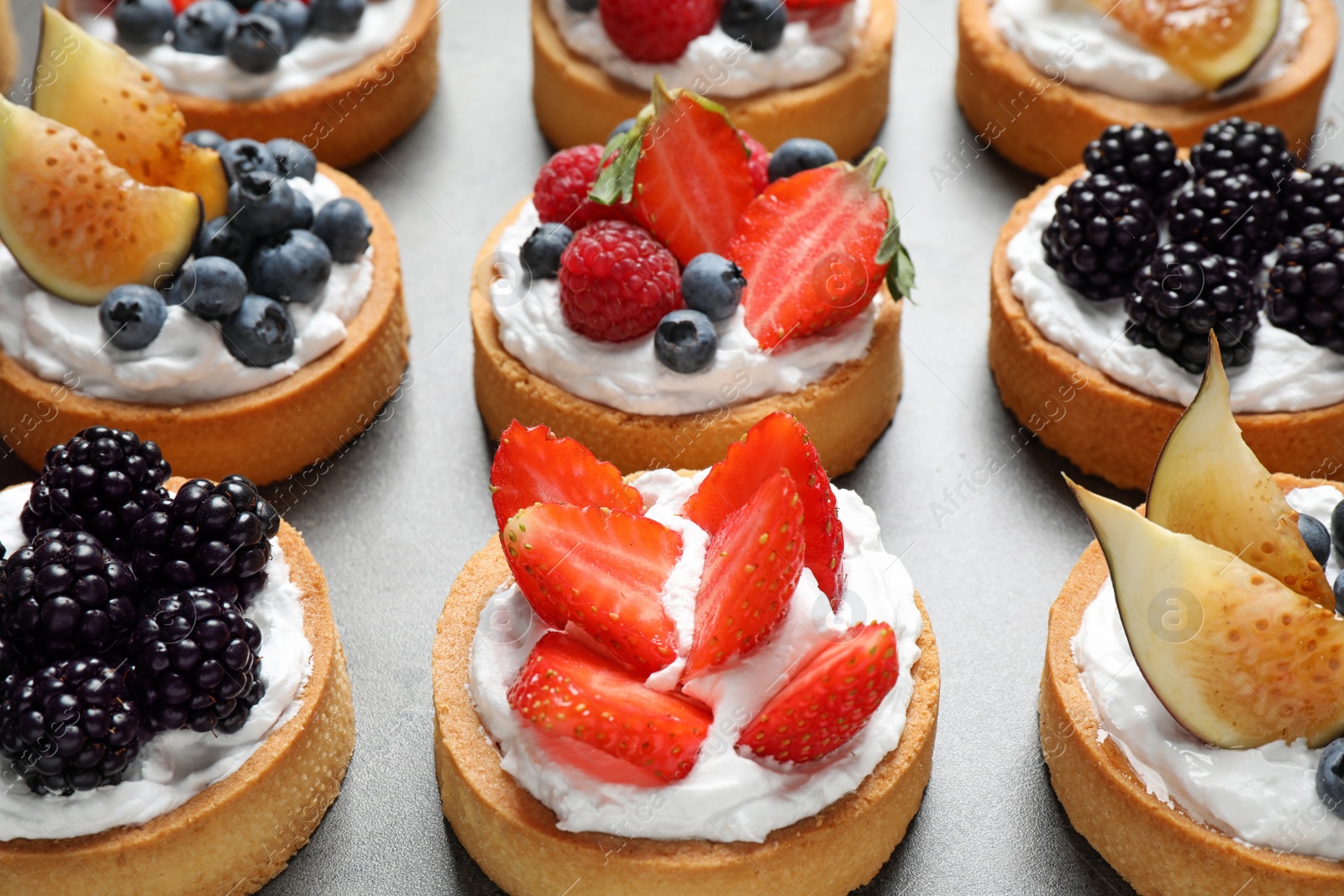 Photo of Many different berry tarts on table. Delicious pastries