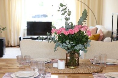 Photo of Beautiful table setting with bouquet of roses, napkins and candles in room