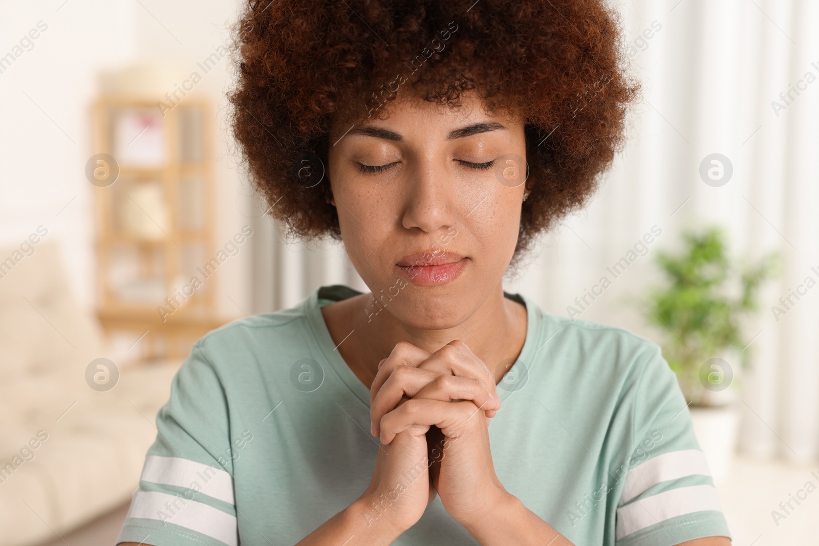 Photo of Woman with clasped hands praying to God indoors