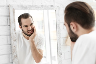 Young man suffering from toothache in bathroom