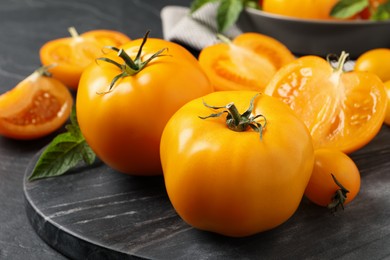 Photo of Fresh ripe yellow tomatoes on black table, closeup