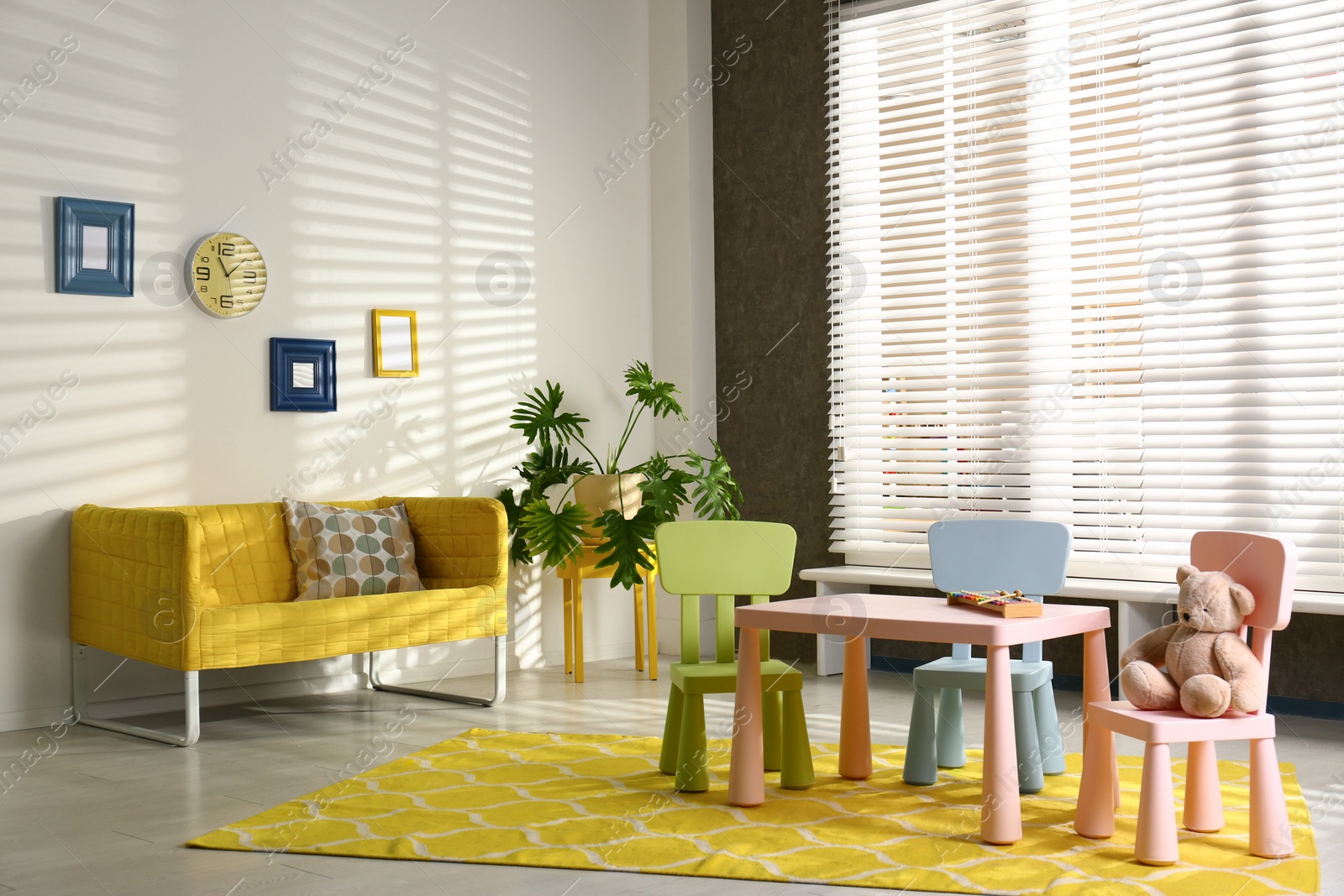 Photo of Stylish playroom interior with table, chairs and sofa