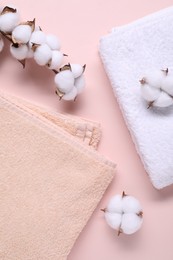 Cotton branch with fluffy flowers and terry towels on beige background, flat lay