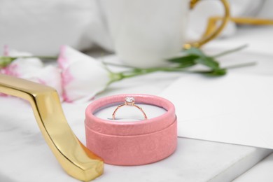 Photo of Tray with beautiful engagement ring in box on white bed, closeup