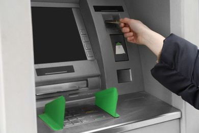 Photo of Woman inserting credit card into cash machine outdoors, closeup