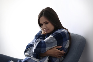 Photo of Depressed young woman in armchair near light wall