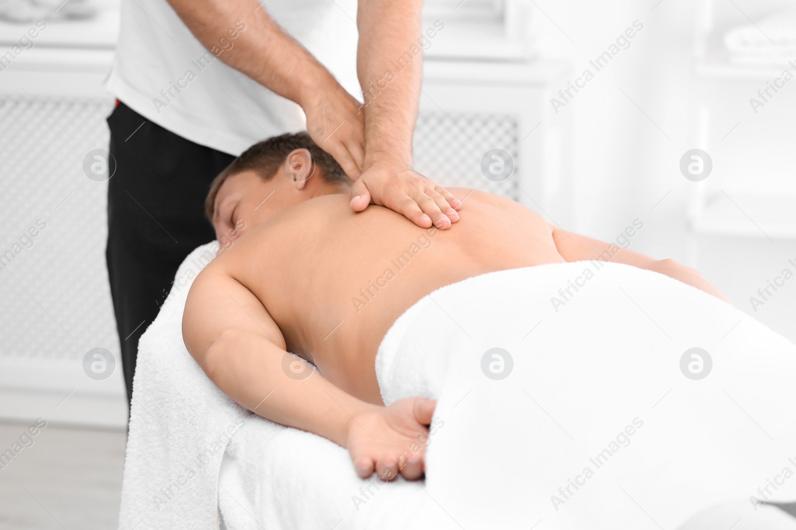 Photo of Relaxed man receiving back massage in wellness center