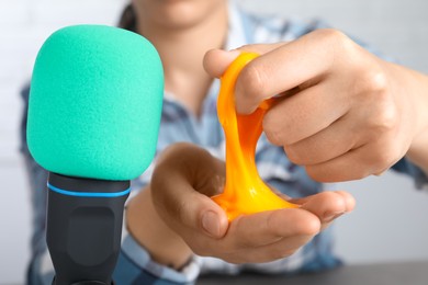 Woman making ASMR sounds with microphone and bright slime, closeup