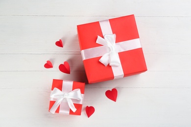 Photo of Gift boxes and paper hearts on white wooden background, flat lay. Valentine's Day celebration