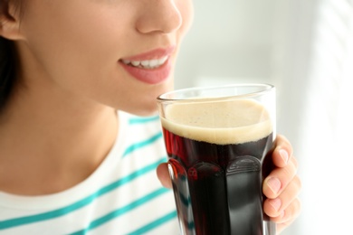 Young woman with cold kvass indoors, closeup. Traditional Russian summer drink