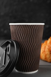 Coffee to go. Paper cup with tasty drink on grey wooden table, closeup