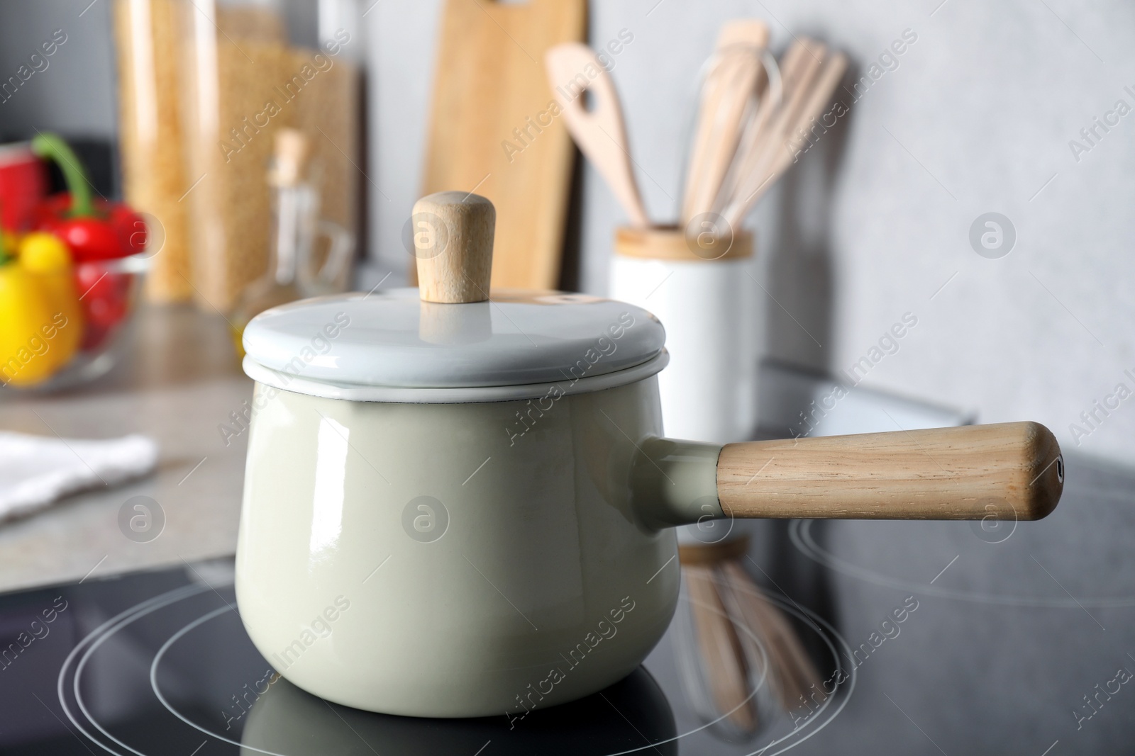 Photo of Saucepan with lid on cooktop in kitchen, closeup view. Cooking utensil