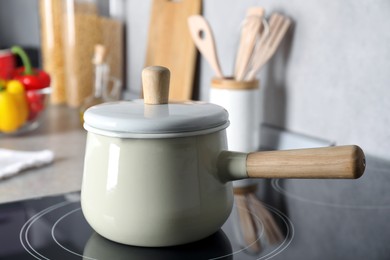 Saucepan with lid on cooktop in kitchen, closeup view. Cooking utensil