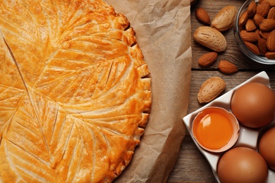 Photo of Traditional galette des rois and ingredients on wooden table, flat lay