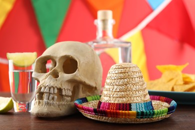 Mexican sombrero hat, human scull and tequila on wooden table