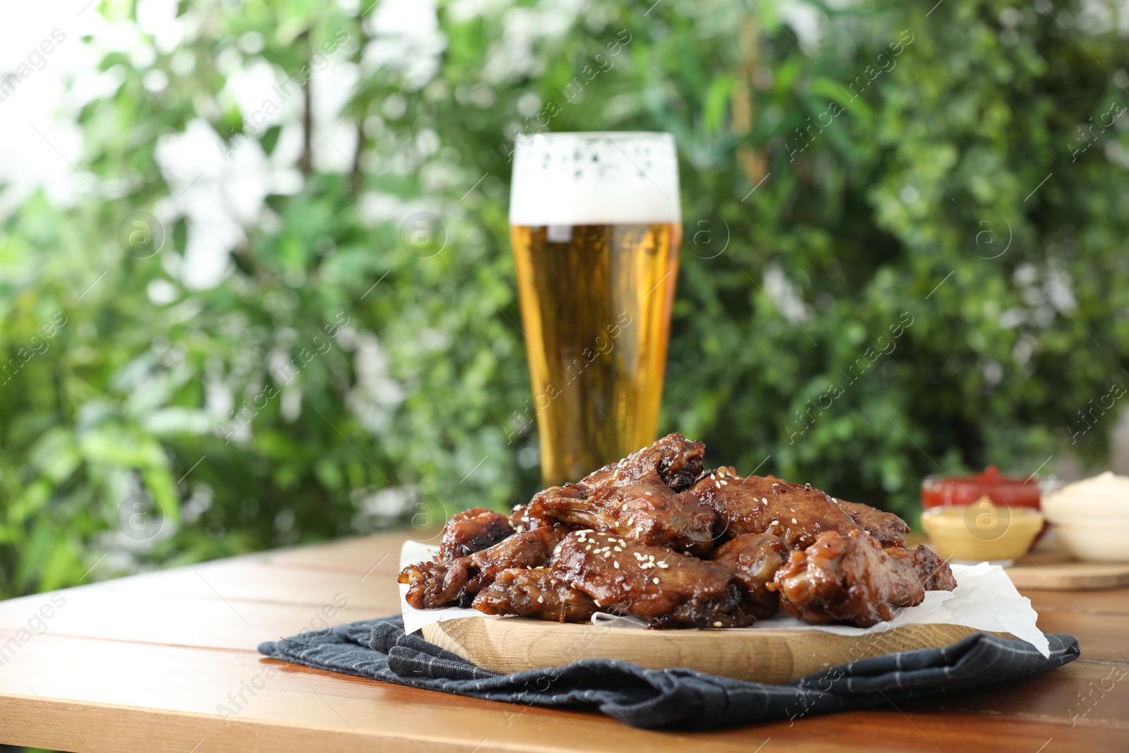 Photo of Tasty roasted chicken wings served with beer on wooden table. Space for text