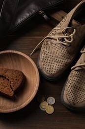 Photo of Poverty. Old shoes, bag, pieces of bread and coins on wooden table, top view