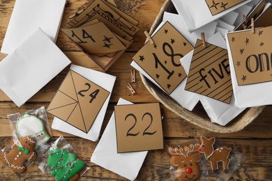 Photo of Flat lay composition with gift bags and Christmas cookies on wooden table. Creating advent calendar
