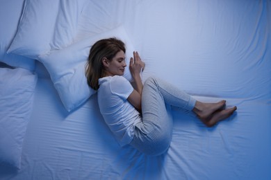 Woman sleeping in bed at night, top view