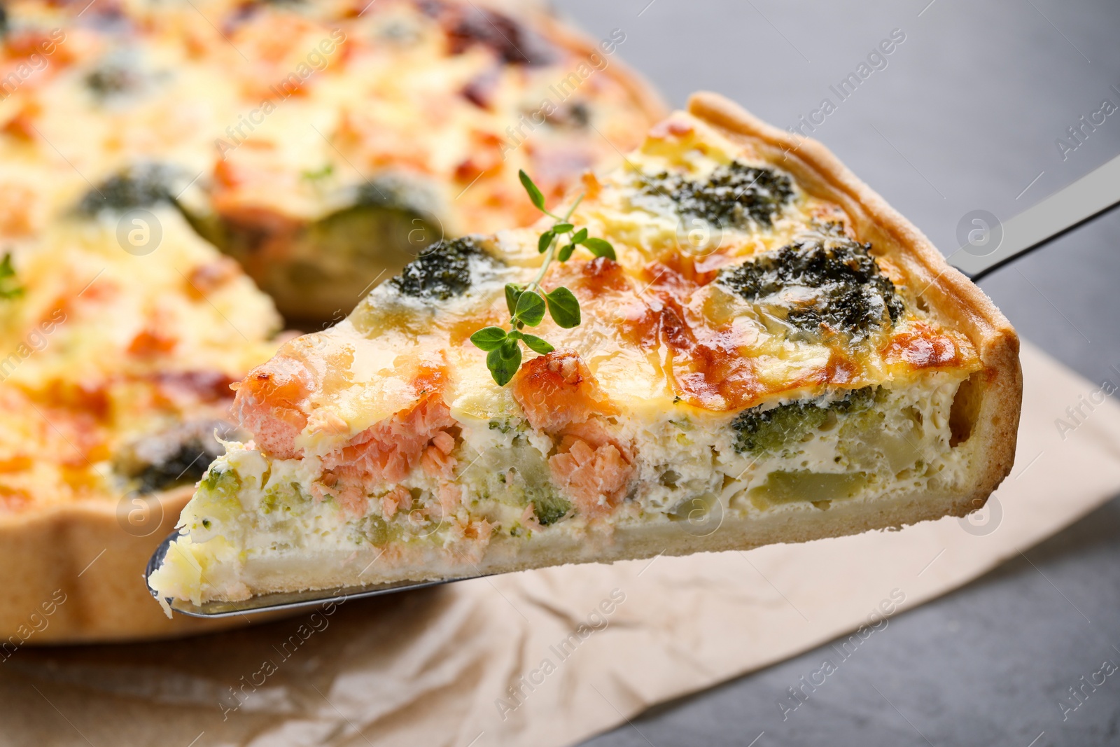 Photo of Spatula with piece of delicious homemade salmon quiche on light background, closeup