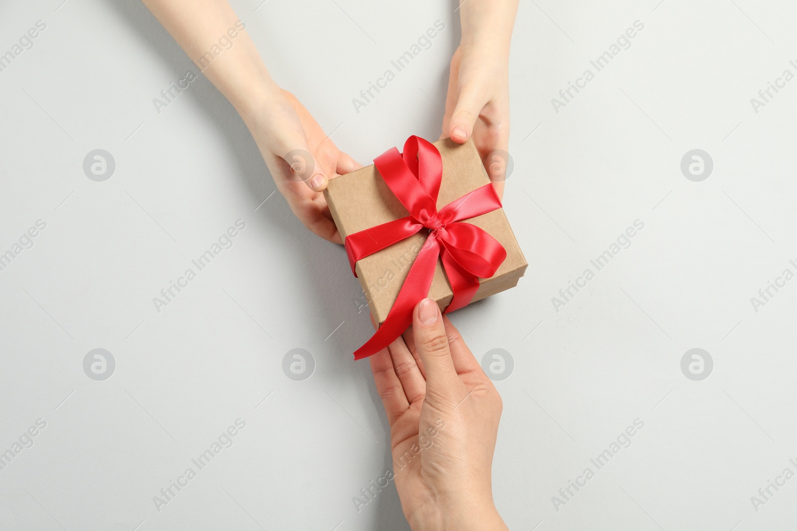 Photo of Mother giving gift box to her child on white background, top view