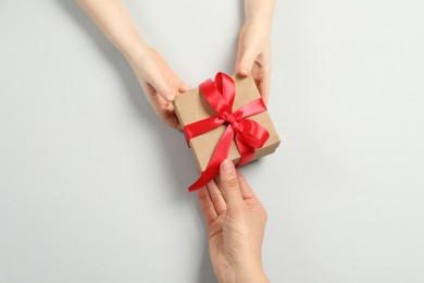 Mother giving gift box to her child on white background, top view