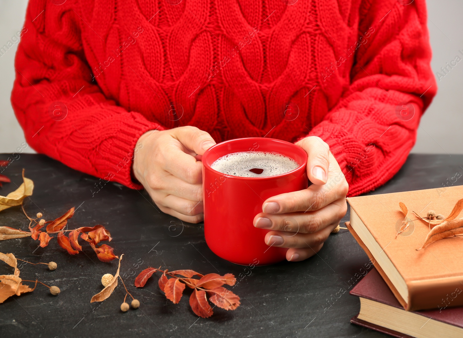 Photo of Woman with cup of hot drink at black table, closeup. Cozy autumn atmosphere