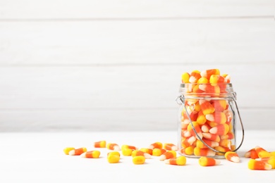 Photo of Jar with delicious candies on table against wooden background. Space for text