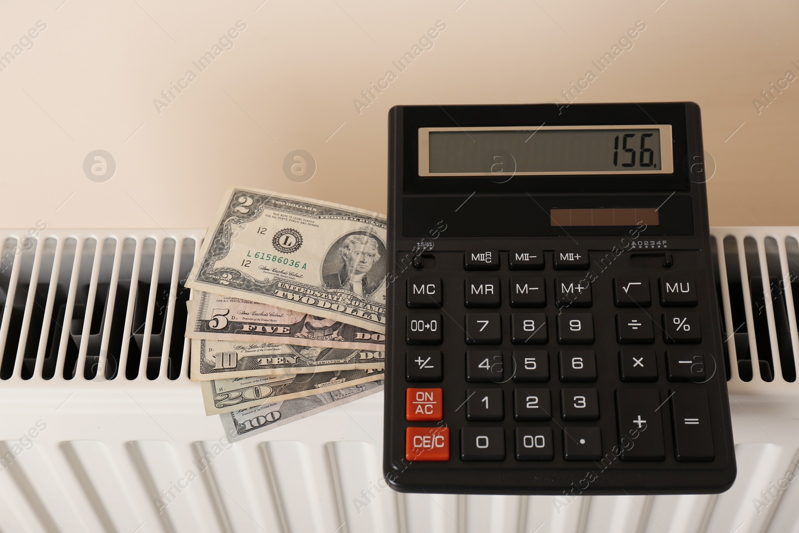 Photo of Heating radiator with calculator and money on color background