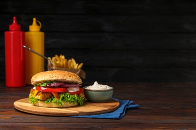 Photo of Delicious tofu burger served with sauce on wooden table, space for text
