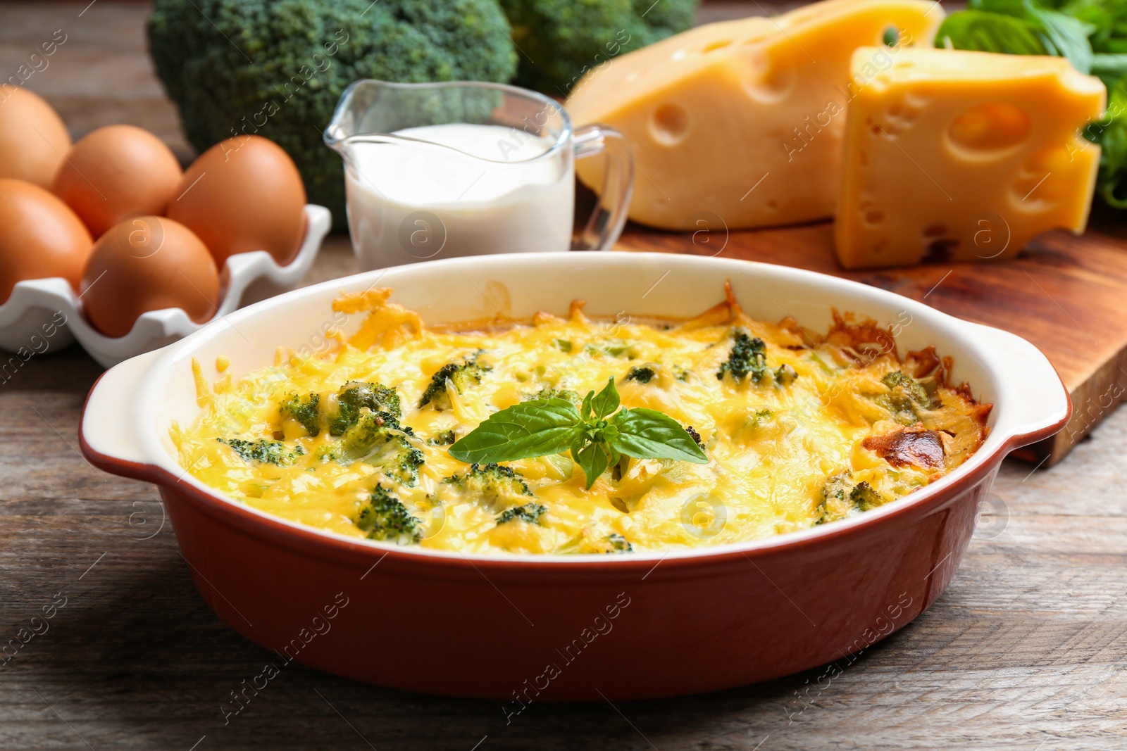 Photo of Tasty broccoli casserole in baking dish on wooden table