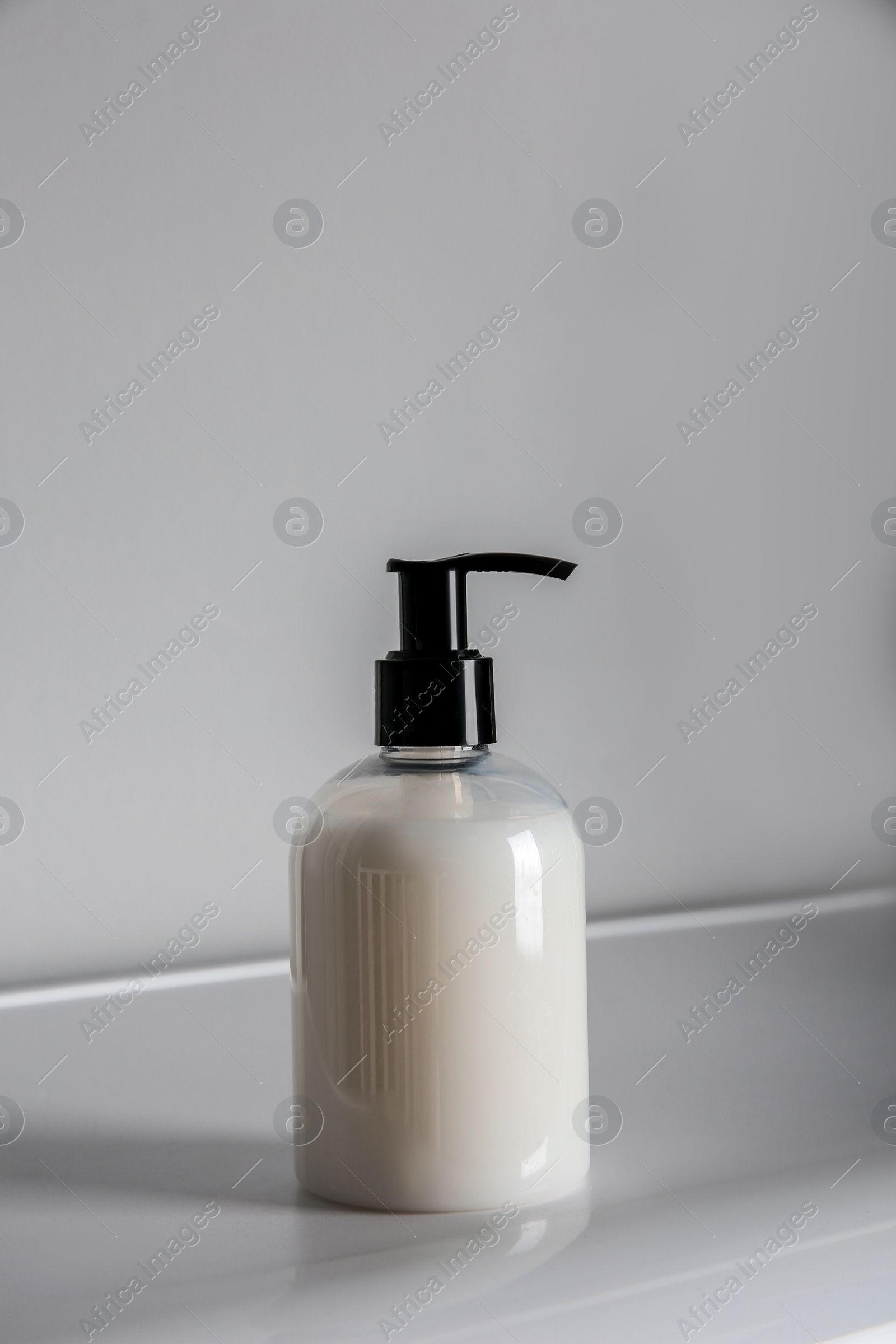 Photo of Bottle of liquid soap on table against light background