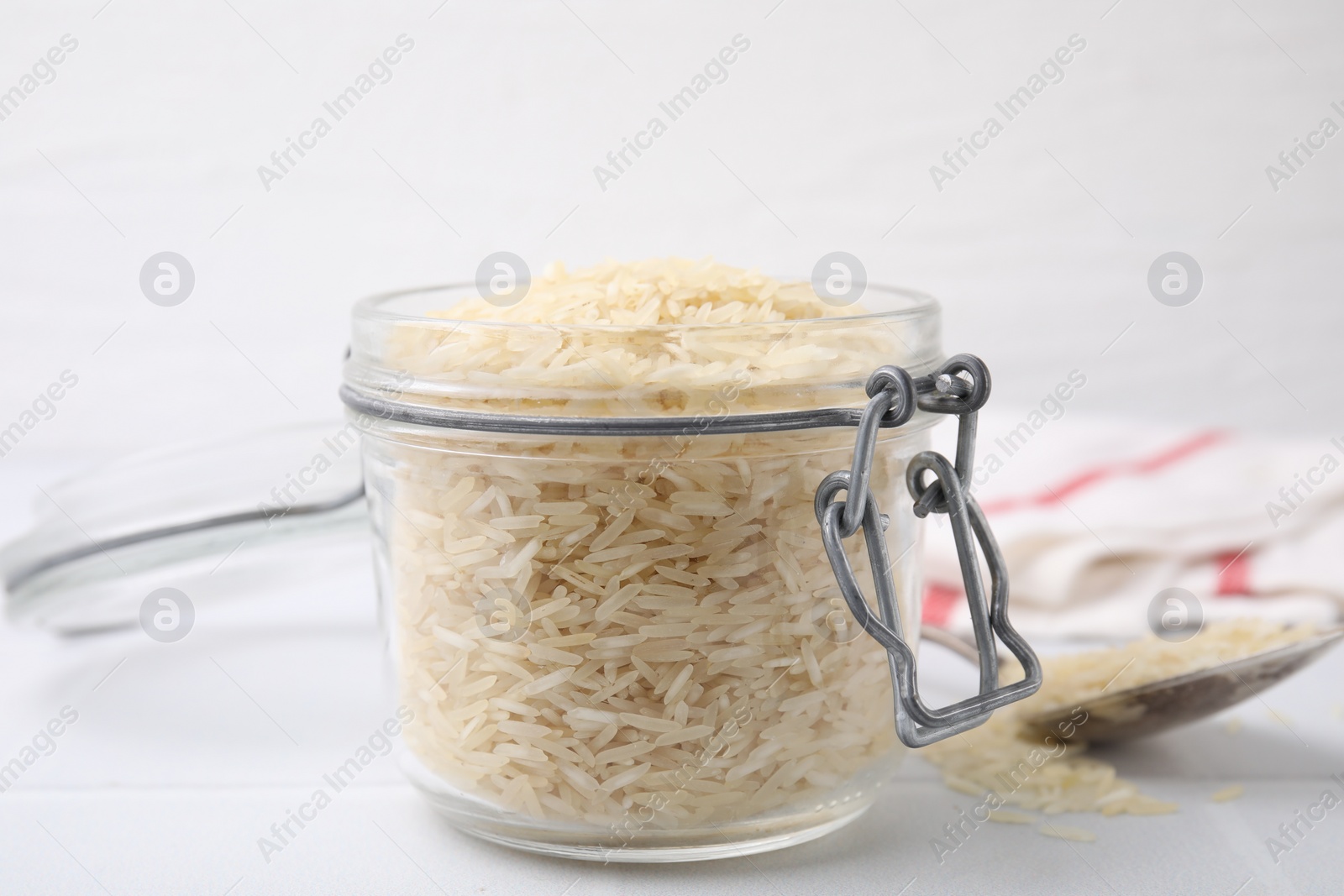 Photo of Raw rice in glass jar on white table, closeup