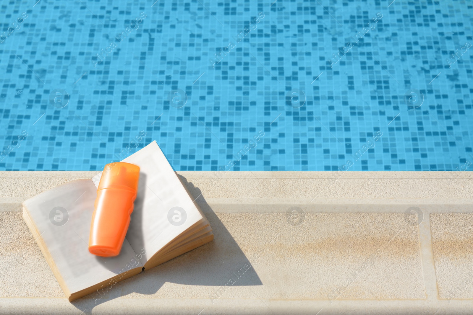 Photo of Open book and sunscreen on swimming pool edge, above view. Space for text