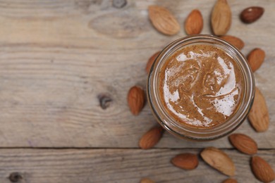 Photo of Tasty almond nut paste in jar on wooden table, top view. Space for text