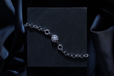 Elegant jewelry. Stylish presentation of luxury bracelet on dark blue podium, top view