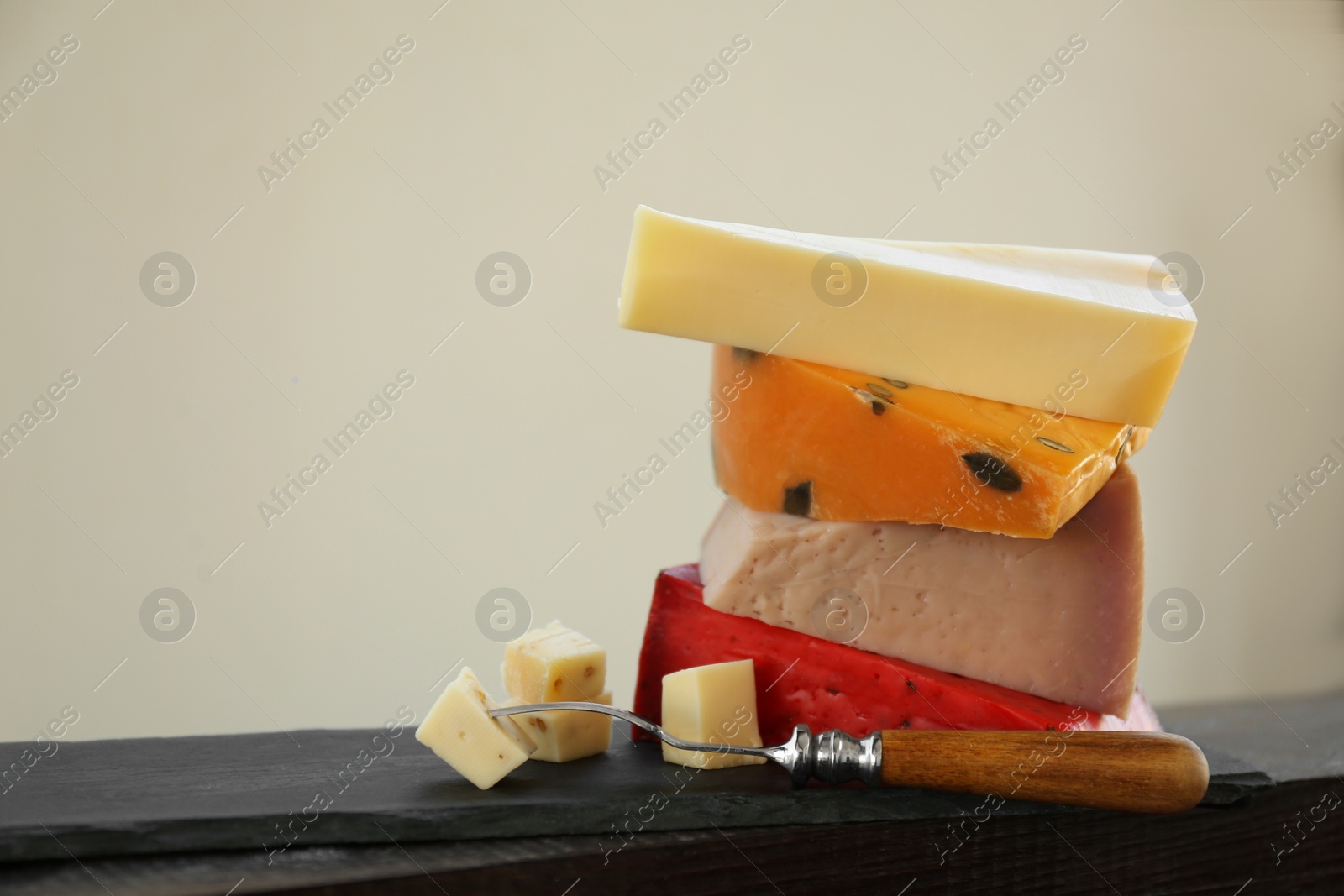 Photo of Different types of delicious cheeses and fork on slate plate, closeup. Space for text