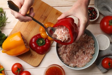 Photo of Woman making stuffed peppers with ground meat at white wooden table, top view