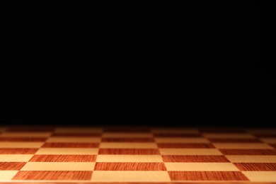 Checkered chessboard on dark background, closeup. Space for text