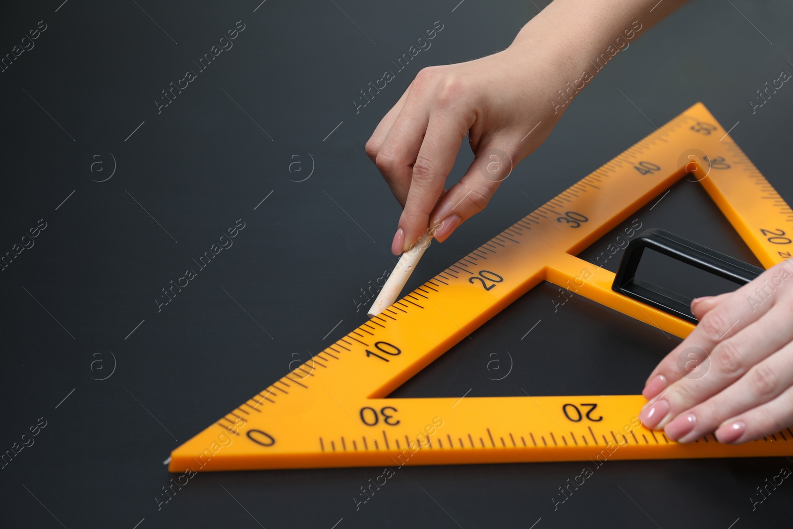 Photo of Woman drawing with chalk and triangle ruler on blackboard, closeup. Space for text