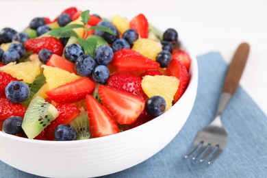 Photo of Delicious fresh fruit salad in bowl served on white table, closeup