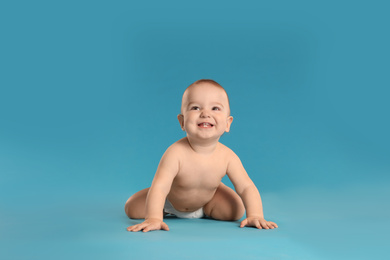 Photo of Cute little baby in diaper on light blue background