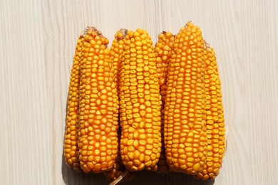 Photo of Delicious ripe corn cobs on white wooden table, top view