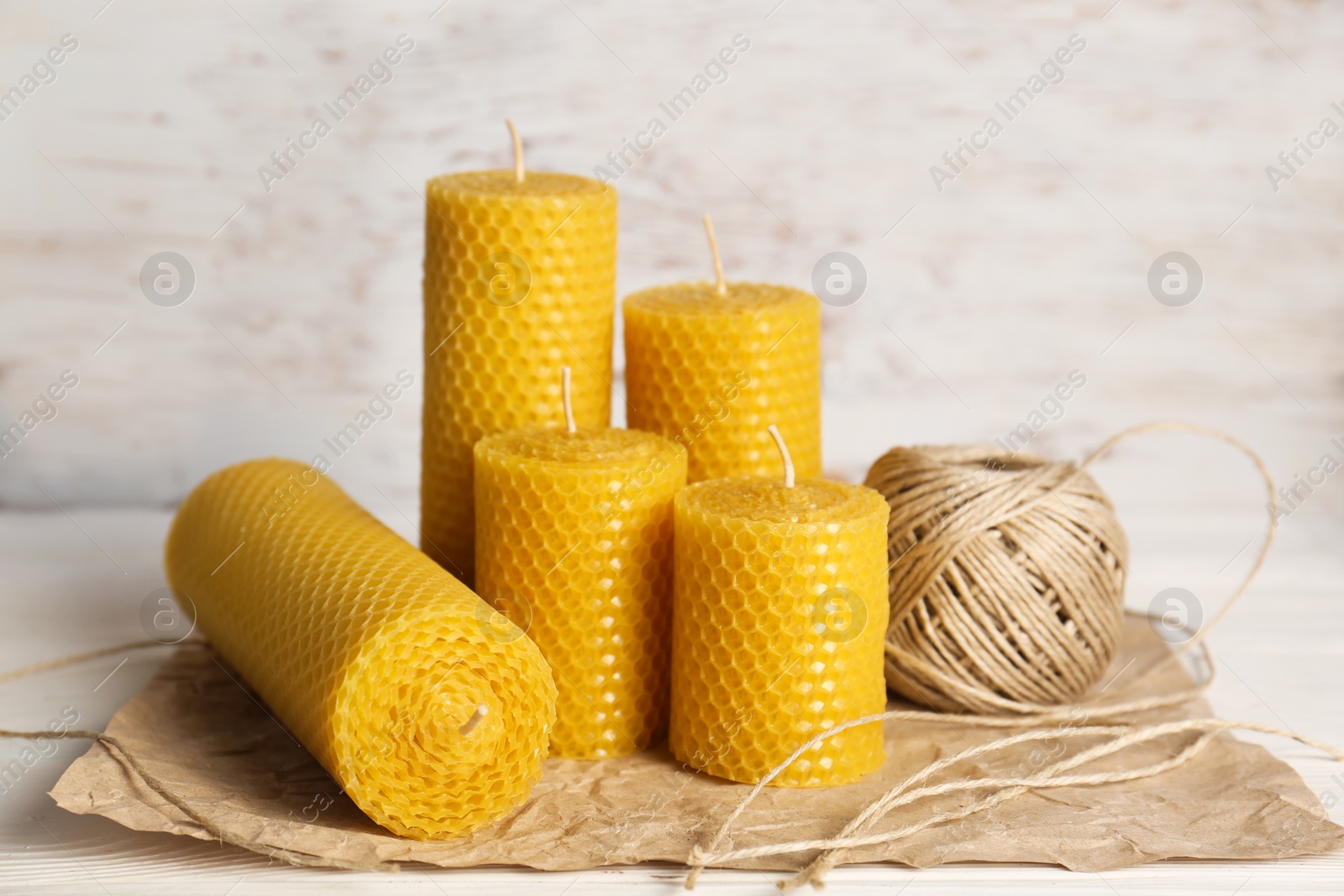 Photo of Stylish elegant beeswax candles and twine on white wooden table