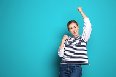 Happy young woman celebrating victory on color background. Space for text