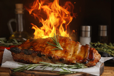 Image of Tasty grilled ribs and flame on wooden table
